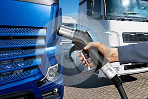 Hand with H2 fueling nozzle on a background of hydrogen fuel cell truck. Eco-friendly commercial vehicle concept..