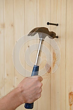 Hand with a hammer hammers a dowel into a wall