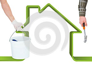 Hand with hammer and hand with a cube in front of a green house