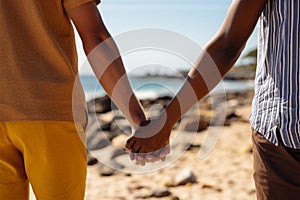 Hand in hand, a biracial gay couple enjoys a sunny beach