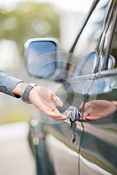 Hand on handle. Close-up of man opening a car door.