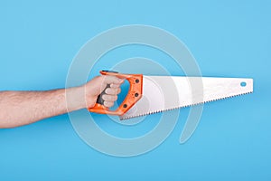 Hand with handsaw, carpentry and construction tool. Isolated on blue background