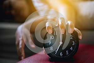 Hand hates getting stressed waking up early,Female stretching her hand to ringing alarm to turn off alarm clock