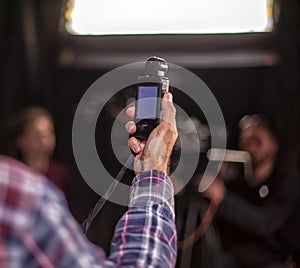 A hand is holding a light meter against black background