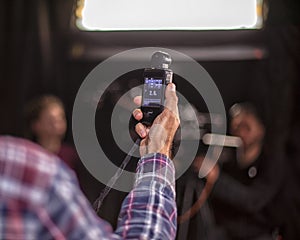 A hand is holding a light meter against black background