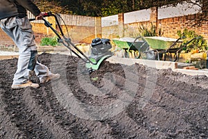 A hand held mechanical rotavator being used to reshape a garden after old turf has been removed