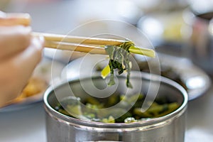 Hand held pickled vegetable in stainless steel food carrier with chopsticks