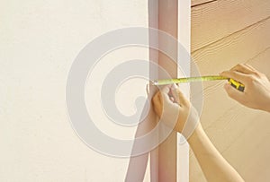 Hand held tape measure the width of the cement edge on the cement wall. Morning sunshine wood background wall