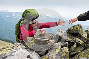 Hand helping hiker to climb the mountain