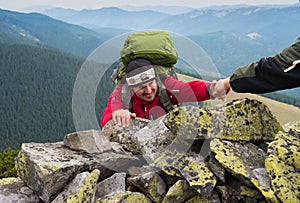 Hand helping hiker to climb the mountain