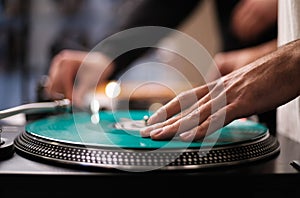 Hand of hip hop dj scratching vinyl record on turntables. Professional disc jockey scratches records on party in night club on
