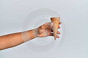 Hand of hispanic man holding biscuit cone over isolated white background