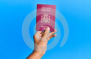 Hand of hispanic man holding spanish passport over  blue background photo