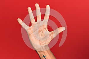 Hand of hispanic man over red isolated background counting number 5 showing five fingers