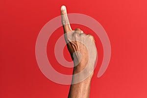 Hand of hispanic man over red isolated background counting number one using index finger, showing idea and understanding