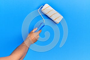 Hand of hispanic man painting blue wall using paint roller