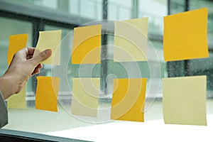 hand hold adhesive notes on glass wall. Sticky note paper remind