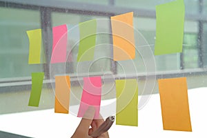 hand hold adhesive notes on glass wall. Sticky note paper remind