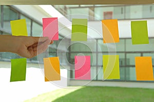 hand hold adhesive notes on glass wall. Sticky note paper remind