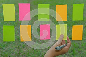 hand hold adhesive notes on glass wall. Sticky note paper remind