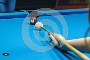 Hand hold a billiard stick on a billiard table ready to hit the