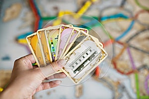 Hand hold cards of Ticket to ride game.