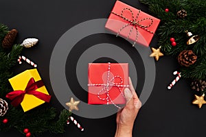 Hand hold christmas gift box with pine tree and xmas decoration on black background