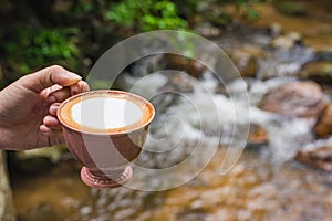 Hand hold a cup of cappuccino at rill.