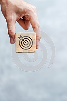 Hand hold dartboard block with business goal, strategy, target, mission, action, objective, aim and success concept