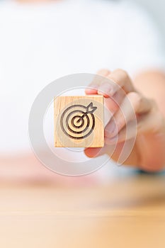 hand hold dartboard block with business goal, strategy, target, mission, action, objective, aim and success concept