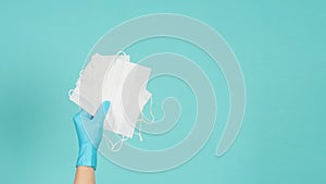 Hand is hold face masks wear blue latex gloves or doctor gloves on mint green or Tiffany Blue background