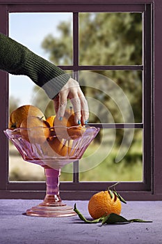 hand hold Fresh ripe mandarine in stand plate near window.