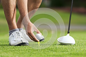 Hand hold golf ball with tee on course