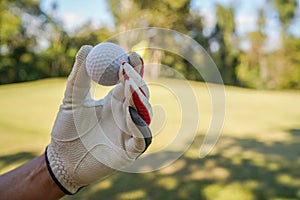 Hand hold golf ball with tee on course, golf course background