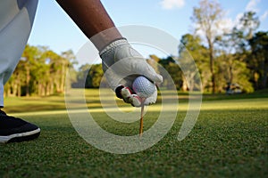 Hand hold golf ball with tee on course, golf course background