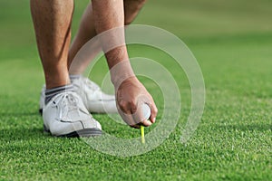 Hand hold golf ball with tee on course