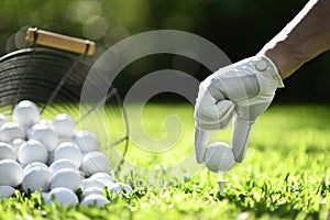 Hand hold golf ball with tee on green grass for practice