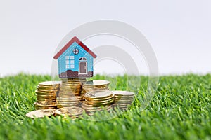 Hand hold a home model put on the stack coin with growing. Savings money for buy house and loan to business investment