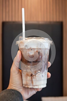 Hand hold ice mocha coffee in a glass with cream