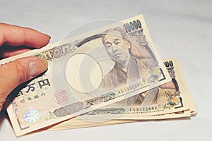 Hand hold a 10000 Japanese currency, bill yen in a crocodile texture Wallet,on white background, a copy space.