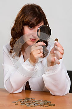 Hand hold magnifying glass and coins