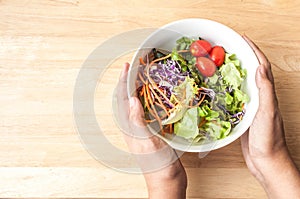 hand hold mixed Salad bowl on wooden table