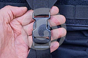 Hand hold a one closed black plastic carabiner on a harness