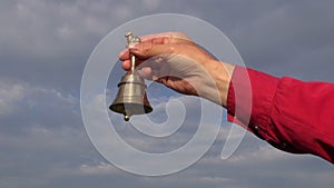 Hand hold ornamental brass bell on blue sky background