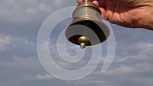 Hand hold ornamental brass bell on blue sky background