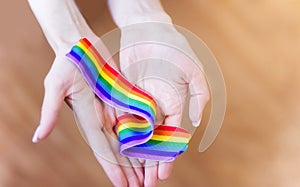 hand hold a rainbow of LGBT tapes on a LIGHT background. Copy space The concept of homosexuals and LGBT people.