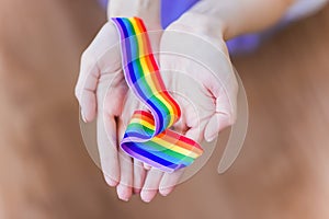 Hand hold a rainbow of LGBT tapes on a LIGHT background. Copy space The concept of homosexuals and LGBT people.