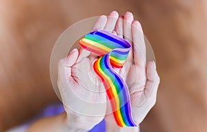 Hand hold a rainbow of LGBT tapes on a LIGHT background. Copy space The concept of homosexuals and LGBT people.