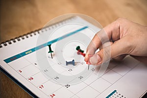 hand hold red push pin to mark date on calendar with vignette