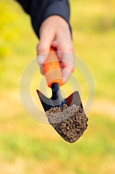 Hand Hold Scoop With Soil In Sunny Day In Garden Close Up